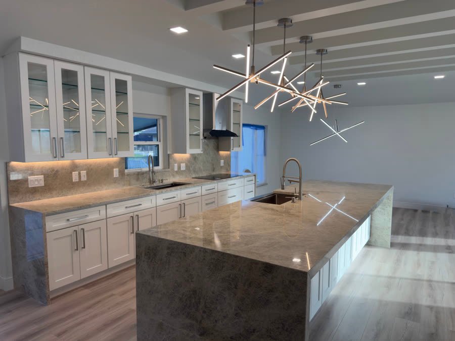 Kitchen remodel with a quartzite waterfall island, white shaker cabinets with glass fronts, and starburst pendant lights