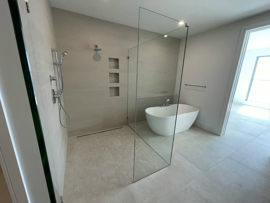 Wet room bathroom with a glass panel, curbless shower and freestanding tub