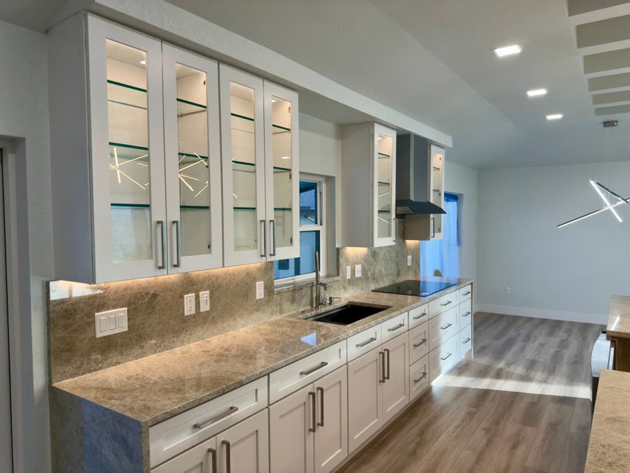 White kitchen with glass front upper cabinets and a stone backsplash
